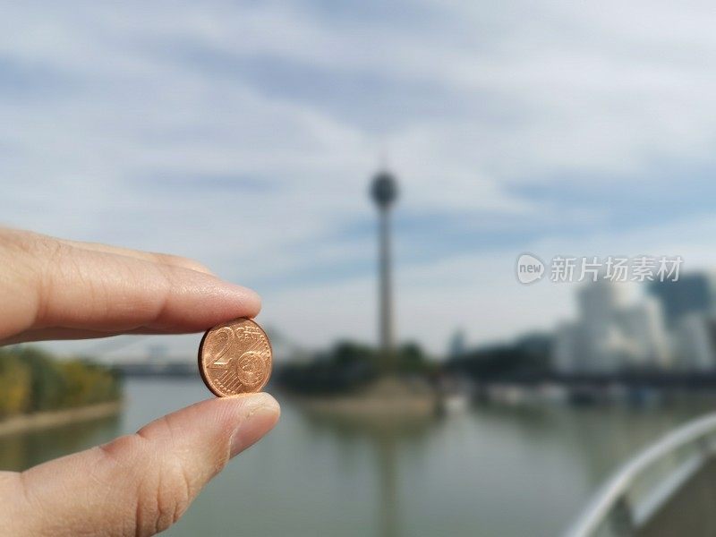 妇女手中的2分欧元硬币手指在背景前面Düsseldorf Medienhafen